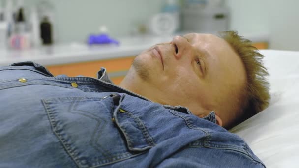 Un hombre en traje de mezclilla recibe terapia intravenosa — Vídeo de stock