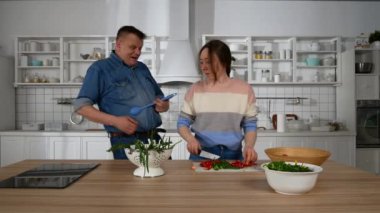 Mutfakta bir kızla dans eden adam.