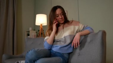 Kız kanepede cep telefonuyla konuşuyor.