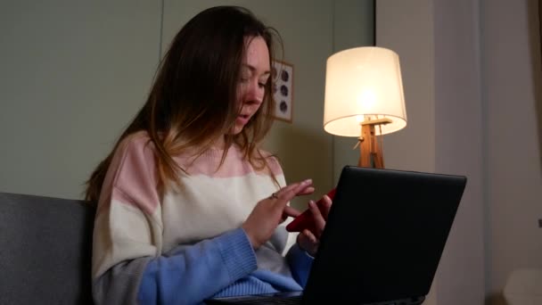 Κορίτσι εργάζεται σε ένα φορητό υπολογιστή και μιλάει στο τηλέφωνο — Αρχείο Βίντεο