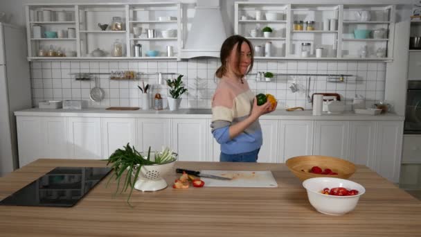 Lány tánc és szeletelés zöldségek a konyhában — Stock videók