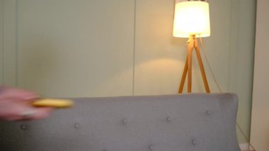 Kız kanepede oturuyor ve cep telefonunda bir şeyler arıyor.