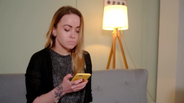 Menina no sofá está assistindo algo no smartphone — Vídeo de Stock