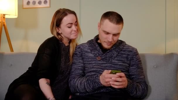 Разочарованная невнимательность, девушка берет смартфон у парня — стоковое видео