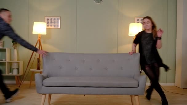 Couple in love runs around the sofa — Stock Video