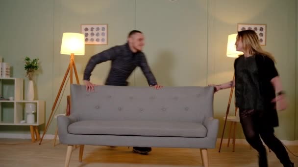 Couple in love runs around the sofa — Stock Video