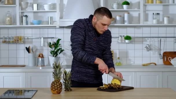 Muž na řezací desce krájí ananas do kruhů — Stock video