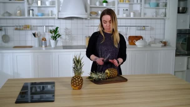 Menina corta abacaxi em pequenos círculos na cozinha — Vídeo de Stock