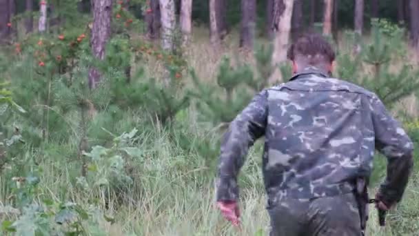 Voják běží mezi mladými borovicemi — Stock video