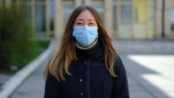 Jonge vrouw in een medisch masker houdt de aarde — Stockvideo