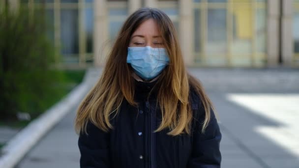 Ung flicka i en medicinsk mask med en glob i mask — Stockvideo