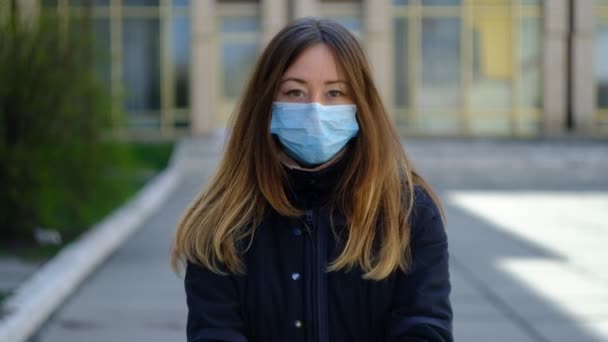 Joven mujer en una máscara médica sostiene la tierra — Vídeo de stock