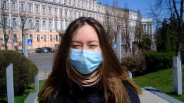 Mavi maskeli kız sokakta yürüyor.