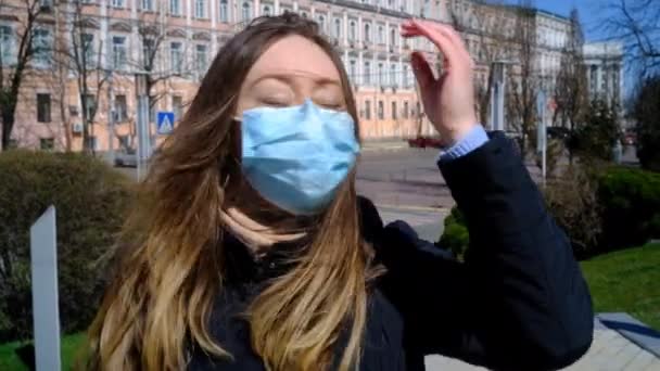 Menina em uma máscara azul caminha em uma rua ventosa — Vídeo de Stock