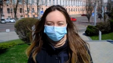 Mavi maskeli kız sokakta yürüyor.