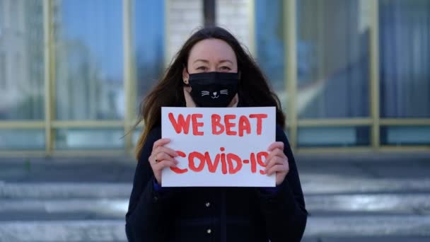 Gemaskerd meisje toont vrolijke poster — Stockvideo