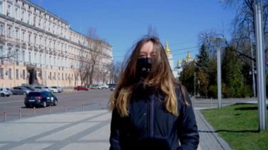 Tıbbi maskeli bir kız sokakta yürüyor.