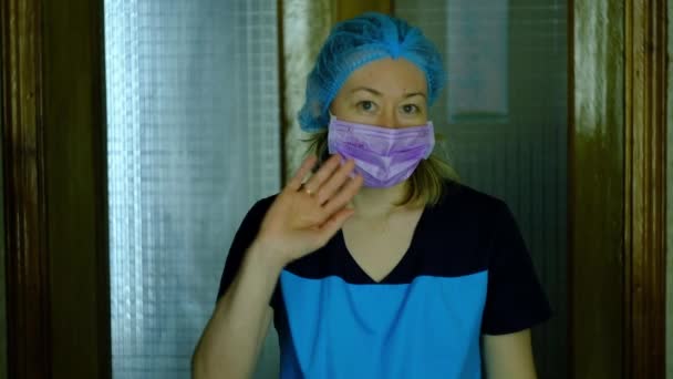 Tıbbi maskeli ve koruyucu şapkalı bir kız doktor afiş gösteriyor. — Stok video