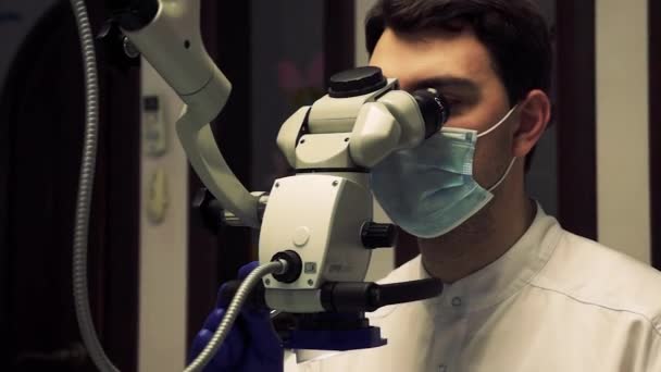 Tandarts kijkt door een moderne microscoop tijdens een procedure — Stockvideo