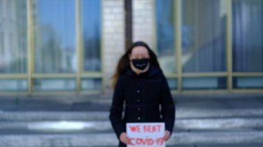 Maskeli bir kız ve bir poster Coronavirus 'a karşı zaferle seviniyor.