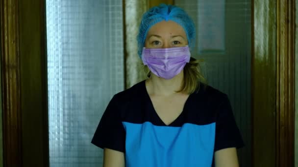 A nurse in a medical mask and a protective cap shows posters — Stock Video