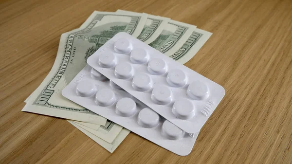 Pills on the table in white plastic and dollars on the table. — Stock Photo, Image