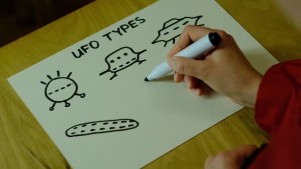 Дівчинка малює на папері різні НЛО. — стокове відео