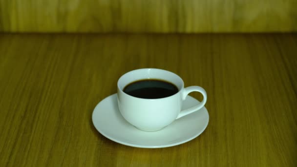 Una tazza bianca piena di chioschi di caffè nero su un piattino — Video Stock