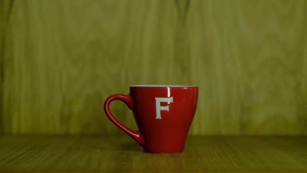 Pequeña taza de café rojo en una mesa de madera — Vídeo de stock