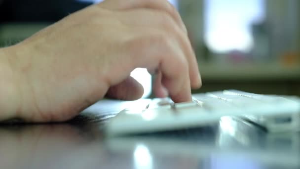 Een man typt tekst op een wit toetsenbord. — Stockvideo