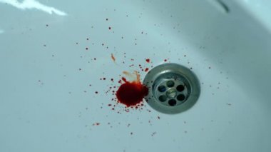 Beyaz bir lavaboya siyah kan damlıyor.
