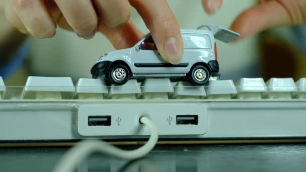 여자 아이가 컴퓨터 키보드에 달린 작은 흰색 자동차 옆에서 노는 모습. — 비디오