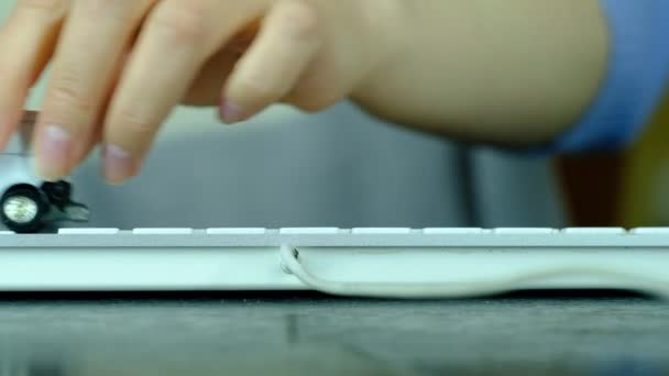Bir kız bilgisayar klavyesinde küçük beyaz bir araba tarafından çalınır.. — Stok video