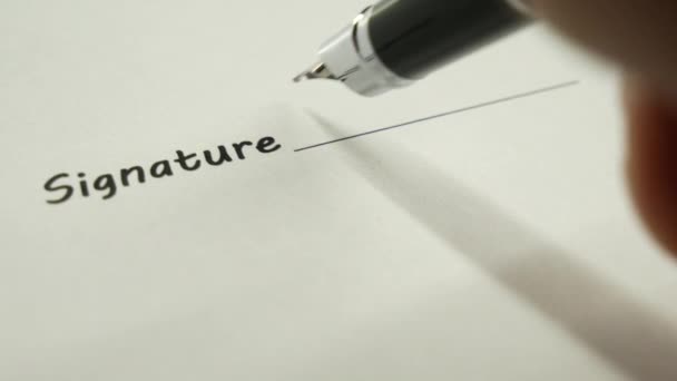 Un homme signe un document avec un stylo à encre .