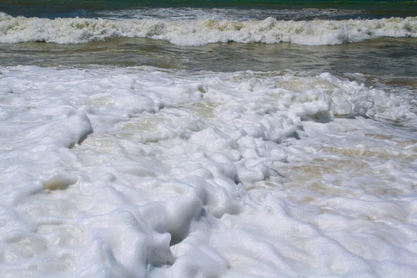Sea foam in the sand after a big wave and surf