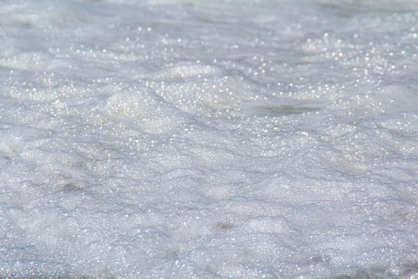 Büyük bir dalga ve sörf sonrası kumda deniz köpüğü