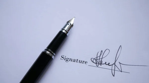 用墨水在重要文件上英俊男子的签名 图库图片