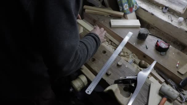 Muž tesař připevňující dřevěné prkno k borovicovému šelfu, aby zkontroloval, zda se hodí podle míry
