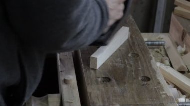 Erkek marangoz çam ağacı rafı için kriko uçağıyla tahta döşeme ve inşaata uygun olup olmadığını kontrol ediyor.