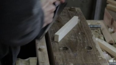 Erkek marangoz çam ağacı rafı için kriko uçağıyla ahşap bir tahta döşeme yapıyor ve boyutuna uyuyor mu diye kontrol ediyor.