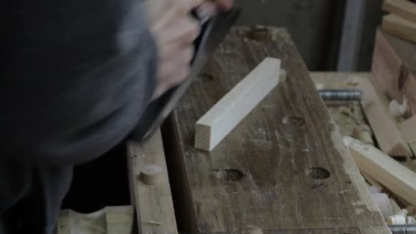 Плотник-мужчина строит деревянную доску с самолетом для сосновой полки и проверяет, подходит ли она по размеру — стоковое видео