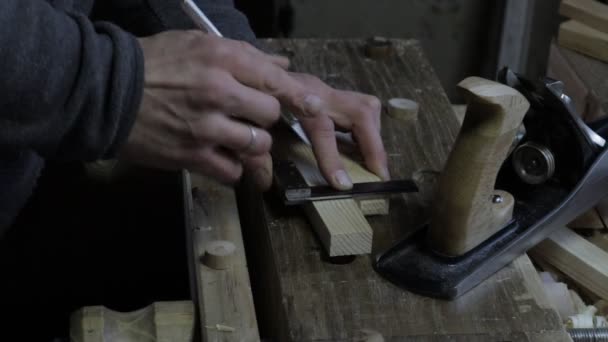 木匠用弯曲的尺子和木匠在松木架上的木板上作标记的男性木匠 — 图库视频影像