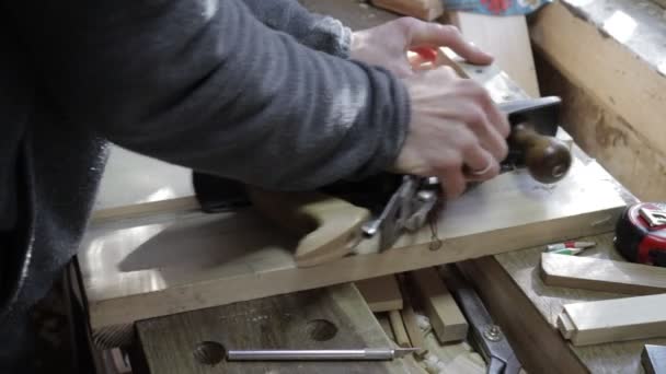 Male carpenter planing of a wooden plank edge with a jack-plane for pine shelf on a jig for perfect 90 degree angle — Stock Video