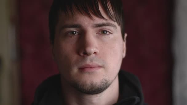 Close-up emotioneel portret van de jonge man met een vriendelijk gezicht geven een lichte glimlach op camera — Stockvideo