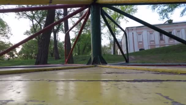 Weitwinkelaufnahme eines sich bewegenden Karussells auf dem Spielplatz. Sicht vom Holzboden aus. — Stockvideo