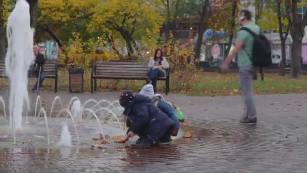 Chernihiv, Oekraïne. 13 okt 2019. Jonge vader en zijn kind spelen bij de fontein op het stadsplein — Stockvideo