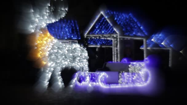 Brillante Navidad renos luces de diseño con casitas en el fondo. Santa trineo, decoraciones de Navidad — Vídeo de stock