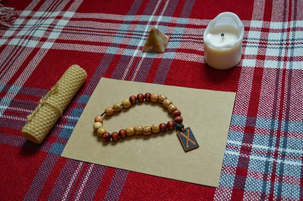 Esoteric and magic things for ritual. Candle, craft sheet, prayer beads, carnelian ring and dark red cloth