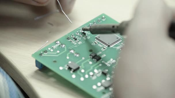 Un travailleur travaille à la création d'une carte électronique. Gros plan . — Video