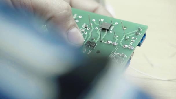 Un travailleur travaille à la création d'une carte électronique. Gros plan .